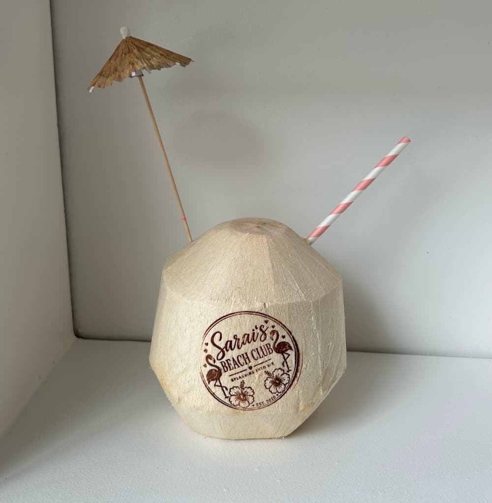 Sarai's Beach Club custom engraved coconut with straw and umbrella